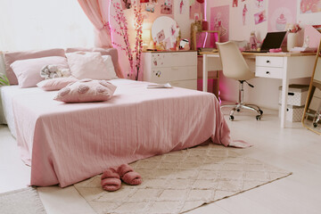 Double bed with pink blanket and cushions, fluffy beige rug near bed and wooden furniture in...