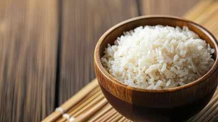 bowl of fluffy white rice sits wooden surface, showcasing its texture and simplicity. warm tones of wood enhance inviting