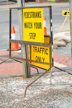 "Pedestrians watch your step" sign on roadside