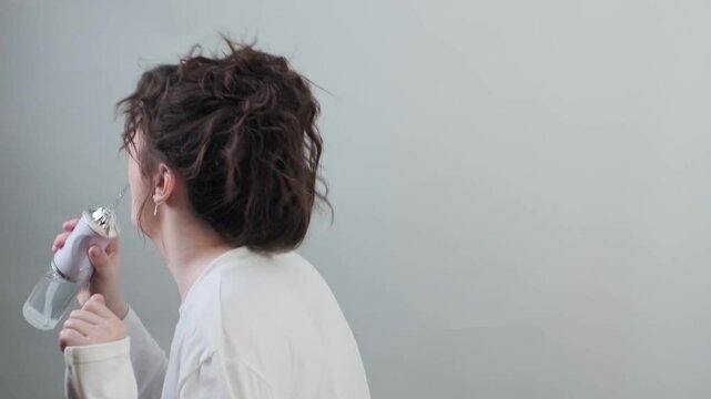 Woman uses water flosser to clean teeth while dancing to favorite music the perfect start to an energetic and happy day.