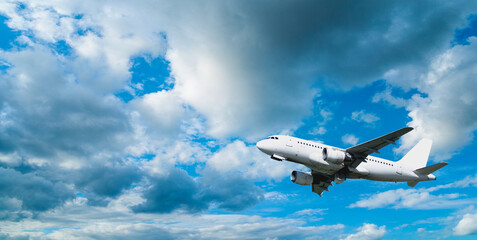 Airplane in the sky, white commercial flying airplane in the flight over the clouds