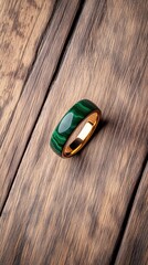 Malachite ring elegantly designed with gold accents placed on a wooden surface