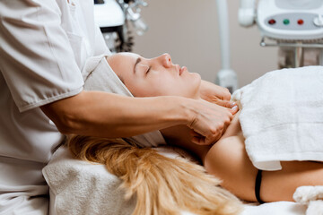 Obraz premium Satisfied mature adult woman receiving professional face and neck massage in beauty spa or salon. Modern cosmetics and beauty concept.