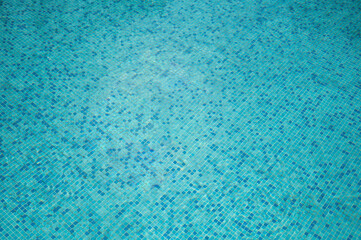 Crystal-clear water rippling over blue mosaic tiles in swimming pool