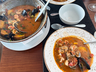 Traditional seafood stew served in a rustic setting, perfect for Mediterranean cuisine lovers and...