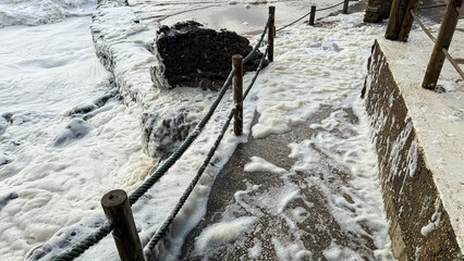 Ocean waves crashing onto a rocky pathway, seascape stormy weather, coastal safety, maritime winter...