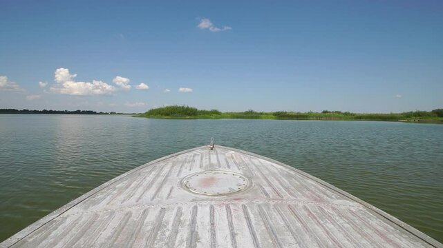 Metal boat sails on water with front view at sunny summer day
