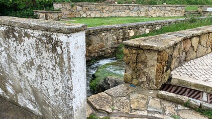 Ancient stone pathway with rustic charm beside flowing stream, perfect for nature retreats and...