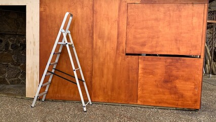 A sturdy ladder leaning against a wooden wall, depicting home improvement, renovation themes...