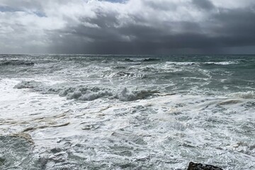 Stormy ocean waves crash under dark clouds, embodying nature's power and freedom, suitable for...