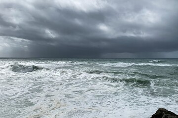 Stormy ocean waves crash under dark clouds, symbolizing nature's power and the unpredictability of weather, Earth Day theme
