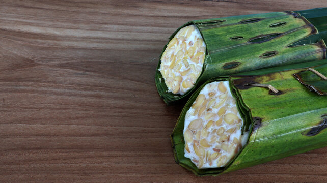 Traditional fermented soybean called tempe wrapped in banana leaves on wooden table