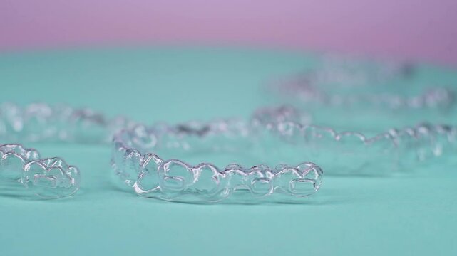 Invisible dental teeth brackets tooth aligners on blue background. Plastic braces dentistry retainers to straighten teeth.