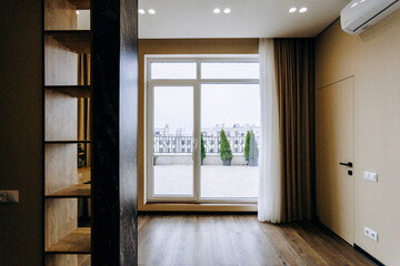 There exists an empty room that features a large window and a balcony