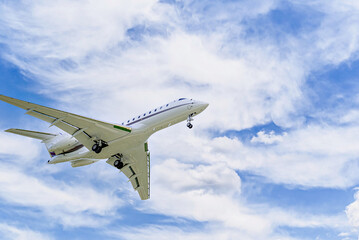 Private business plane flying under a blue sky with white clouds	