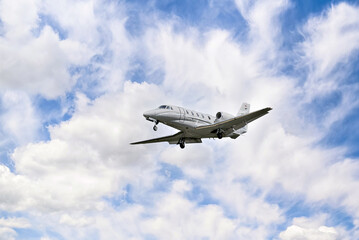 Private business plane flying under a blue sky with white clouds	
