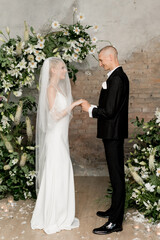 Beautiful happy wedding couple standing at the arch smiling at each other