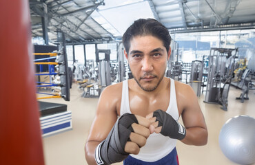 Asian man intensely training Muay Thai in a gym. Powerful punch, focused expression