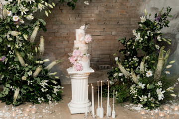 Wedding cake decorated with flowers near the arch