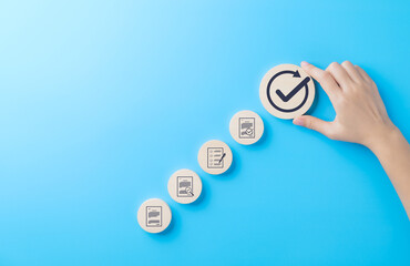 Quality control and certification process concept. A hand places wooden block with checkmark icon in step-by-step symbolizing process of document review, checklist, approval, and quality certificate.