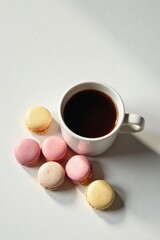 Obraz premium Aromatic Coffee Accompanied by Delicate Pastel-Colored Macarons on a Pristine White Surface