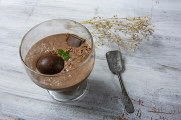 Chocolate mousse dessert in a glass on a white wooden background