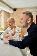 Romantic evening at a cozy bar with a stylish mature couple sharing laughter and drinks