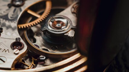 The close-up video captures an antique pocket watch in motion. A rotating spring and textured gears reveal golden details and precise mechanical design, showcasing vintage artistry and craftsmanship.