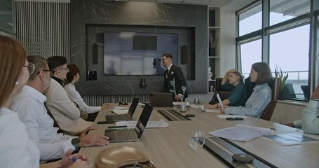 A businessman with crutches leads a presentation, demonstrating inclusivity and resilience in the workplace as he engages with his team.