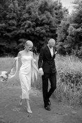 Beautiful wedding couple walking in the park holding hands