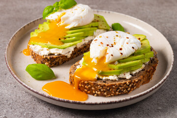 Toast with avocado, soft cream cheese, rye bread and poached Egg. Wholemeal open sandwich for healthy breakfast concept