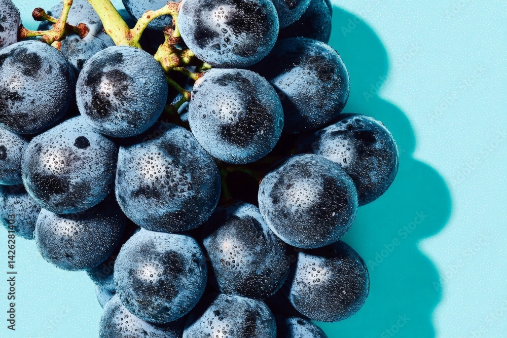 Poster fresh grapes covered in droplets resting on a blue surface showcasing vibrant colors and textures