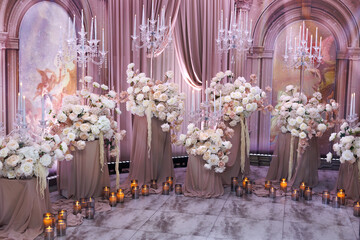 Floral wedding background with lush arrangements of white and pink flowers, candles and spotlights.