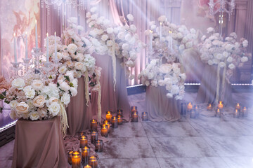 Floral wedding background with lush arrangements of white and pink flowers, candles and spotlights.