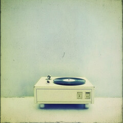 Vintage turntable playing vinyl record against a textured wall; nostalgic music background for blogs or websites