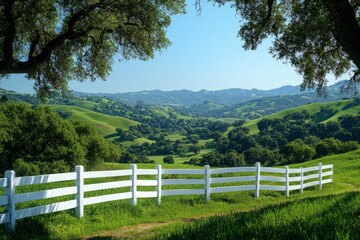 Scenic view of rolling green hills with a white fence under clear blue sky