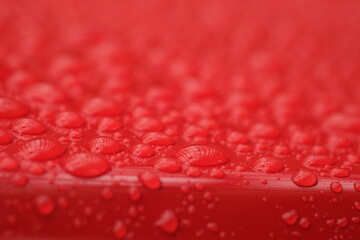 water droplets on the surface of a red shiny surface
