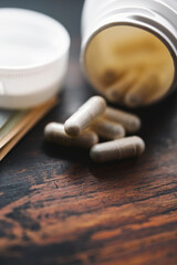 White medicine capsules and medication pills with US dollar banknotes, close-up view