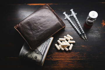 White capsules, narcotics or medicine, syringes and glass vial with substance, wallet and US dollar...