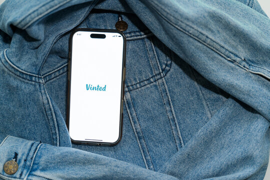 Iphone with vinted logo on screen on vintage denim fabric. Vinted is a Lithuanian online marketplace and community for second hand clothes and accessories.