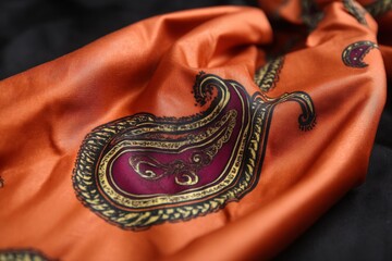Fototapeta premium Vibrant orange fabric with intricate paisley design in close-up showcasing detailed craftsmanship and rich colors