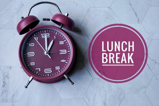 A maroon analog alarm clock with white numbers and hands,  displaying the time as 1 o'clock with text 'LUNCH BREAK' visually emphasizing a designated meal time. - Powered by Adobe