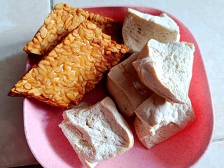 image of fried tempeh and boiled tofu on a pink plastic plate