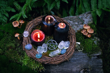 burning black candles, amulet and quartz crystals in forest, dark natural background. occult...
