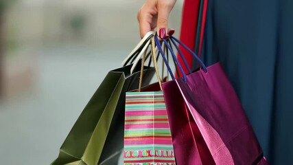 Bright shopping bags hang from womans hand, moment of chic fashion indulgence. Shopping bags evoke joy of luxury retail and colorful essence of successful shopping spree