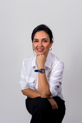 A woman wearing a white shirt and black pants is smiling and holding her wrist