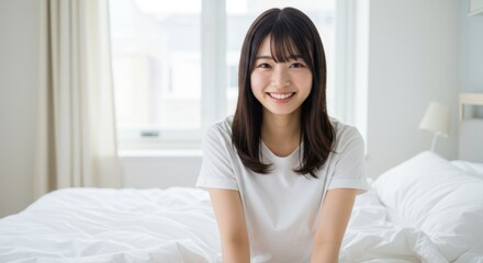 Cheerful young Asian woman sitting in bed and smiling at camera