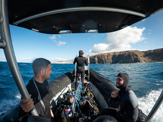 Scuba divers enjoying boat ride to dive site, wide-angle action shot