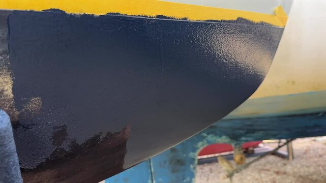 Applying antifouling paint to sailboat hull with roller brush