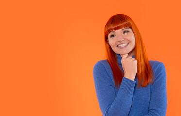 Smiling woman with orange hair expressing joy and confidence against a vibrant orange background...